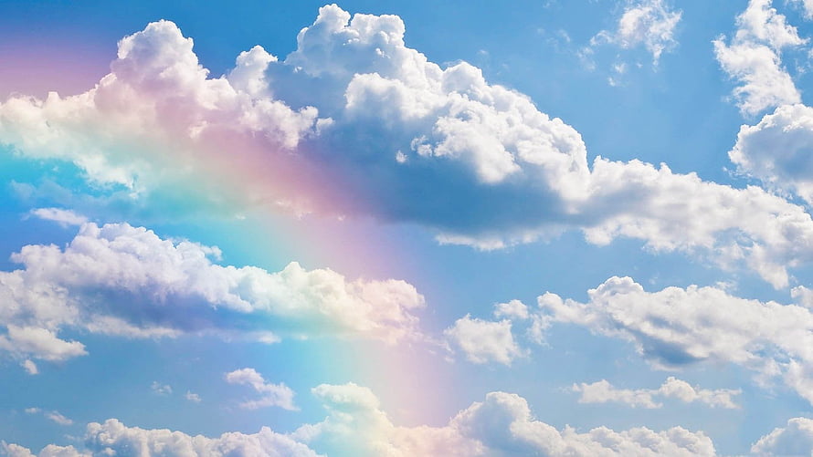 Vibrant Rainbow Beam Piercing Through Fluffy Cumulus Clouds in a Bright Blue Sky HD wallpaper