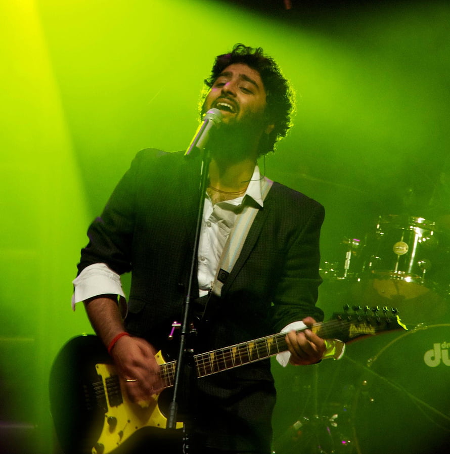 Arijit Singh performing live on stage with electric guitar under green concert lighting HD phone wallpaper