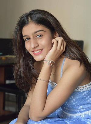 Aadhya Anand in a blue floral dress with a warm smile and colorful beaded bracelets HD phone wallpaper