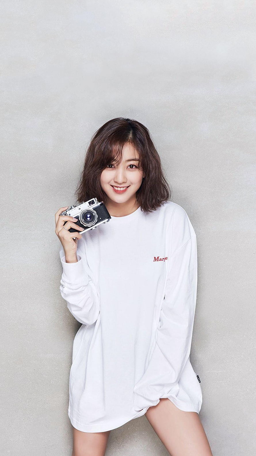 Jihyo from Twice in a white oversized dress holding a vintage camera against a neutral studio backdrop HD phone wallpaper