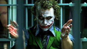 Joker in Green Suit Behind Prison Bars with White Face Paint and Red Lips HD wallpaper