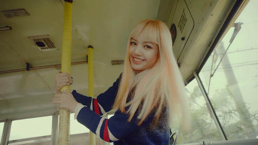 Lisa from BLACKPINK smiling inside a bus with blonde hair and striped sweater HD wallpaper