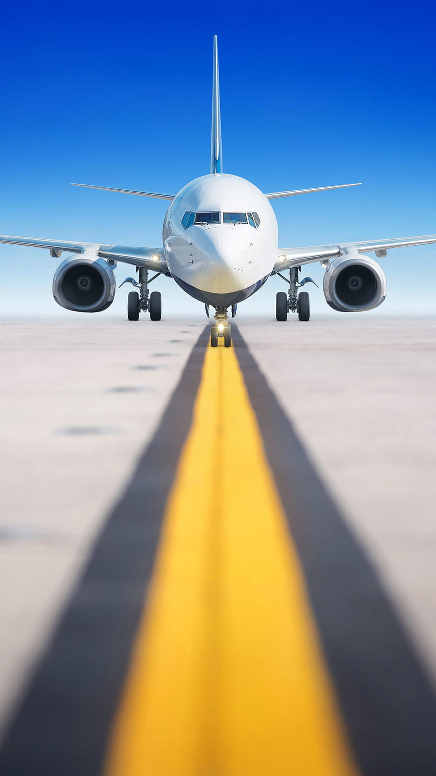 Front View of a Commercial Jet Airliner on a Runway Centerline Under a Clear Blue Sky HD phone wallpaper