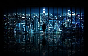 Silhouette of a man gazing at the New York City skyline at night through a floor-to-ceiling window HD wallpaper