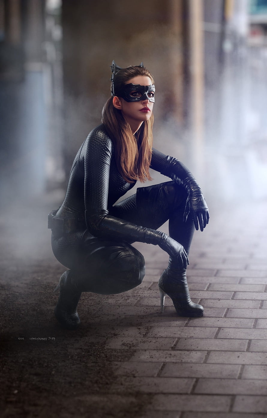 Anne Hathaway as Catwoman in a black leather bodysuit crouching in a misty urban alley HD phone wallpaper