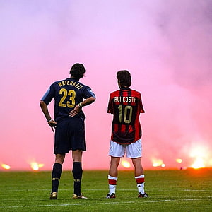 Marco Materazzi and Rui Costa standing on the pitch with pink smoke in the background HD phone wallpaper
