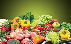 Vibrant assortment of fresh produce including peppers, tomatoes, potatoes, and leafy greens on a green background HD wallpaper
