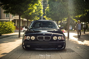 Black BMW E34 M5 Sedan Parked on a Tree-Lined City Street HD wallpaper