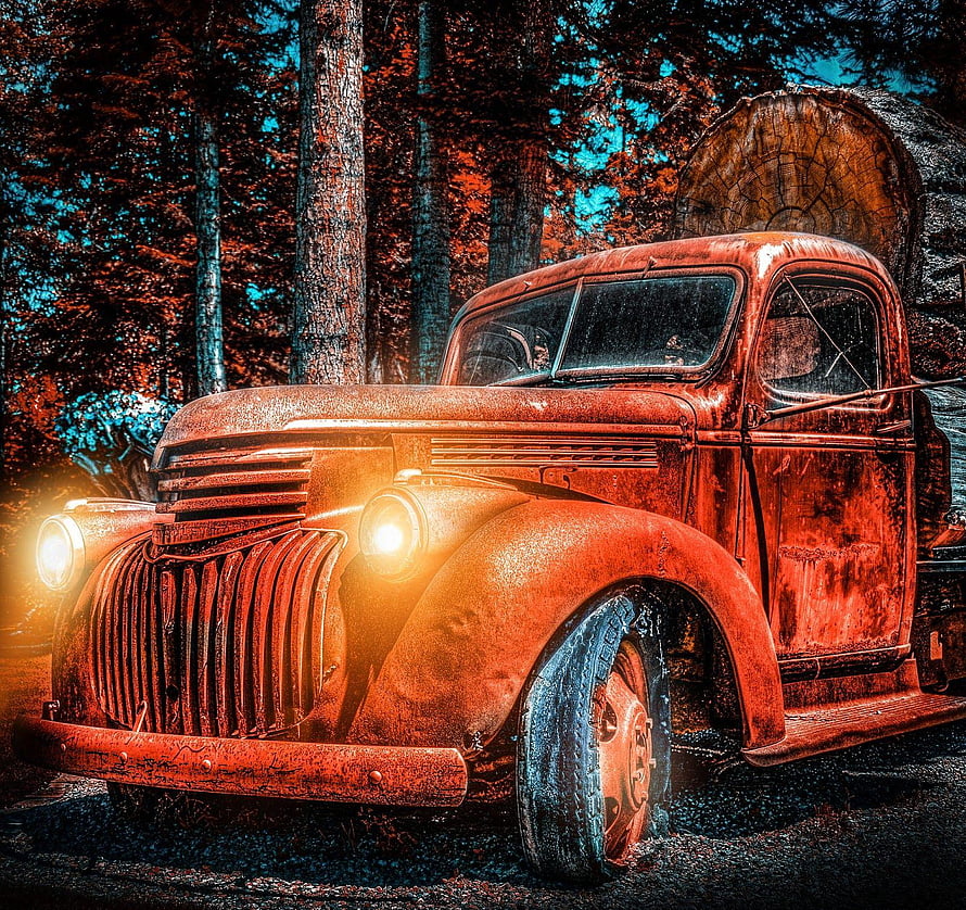 Rusty Vintage Pickup Truck with Glowing Headlights in a Dark Forest Setting HD wallpaper