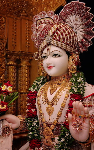 Ornate Swaminarayan Deity Idol Adorned in Gold Jewelry and Floral Garlands HD phone wallpaper