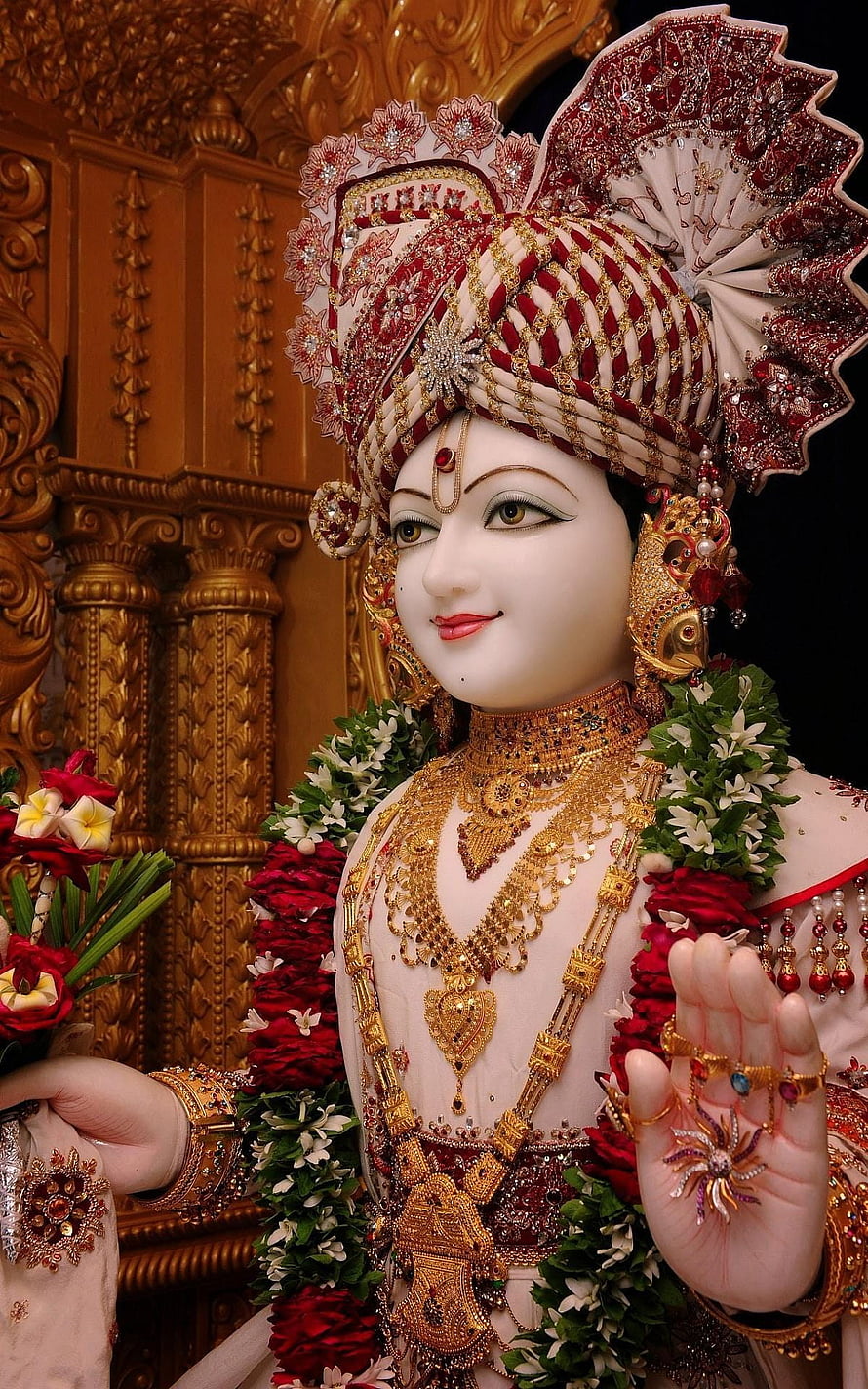 Ornate Swaminarayan Deity Idol Adorned in Gold Jewelry and Floral Garlands HD phone wallpaper