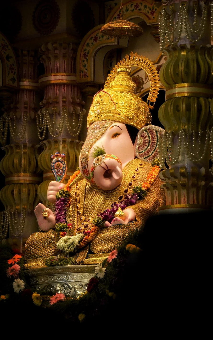 Ornate Ganesha Murti Adorned in Gold Jewelry and Flower Garlands Within a Temple Shrine HD phone wallpaper
