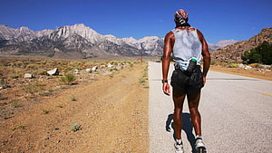 David Goggins Running on Desert Road with Mountain Backdrop HD wallpaper
