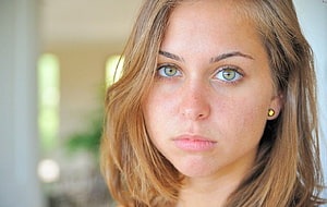 Close-up portrait of Riley Reid with striking green eyes and wavy blonde hair HD wallpaper