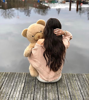 Woman with long dark hair sitting on a wooden dock holding a large teddy bear by a calm lake, Girls Pic Hidden Face With Teddy, girls hidden dp HD phone wallpaper