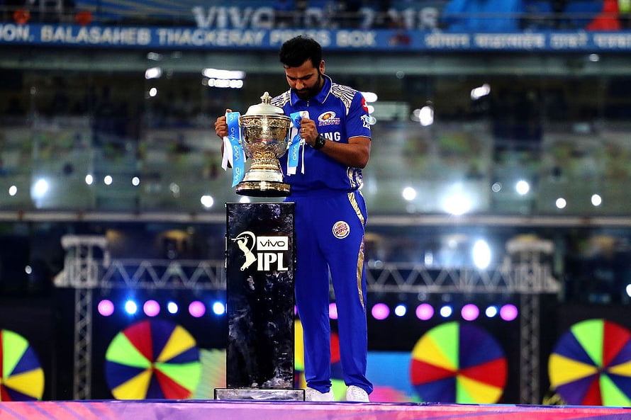Rohit Sharma holding the IPL trophy on the stadium podium in a Mumbai Indians jersey HD wallpaper