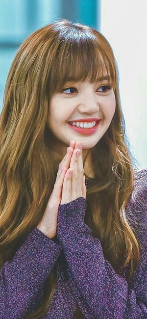 Lisa from Blackpink smiling warmly with hands pressed together in a purple knit sweater HD phone wallpaper