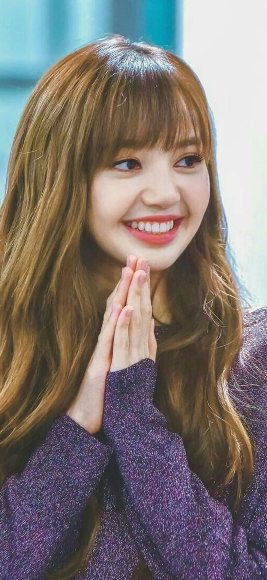 Lisa from Blackpink smiling warmly with hands pressed together in a purple knit sweater HD phone wallpaper