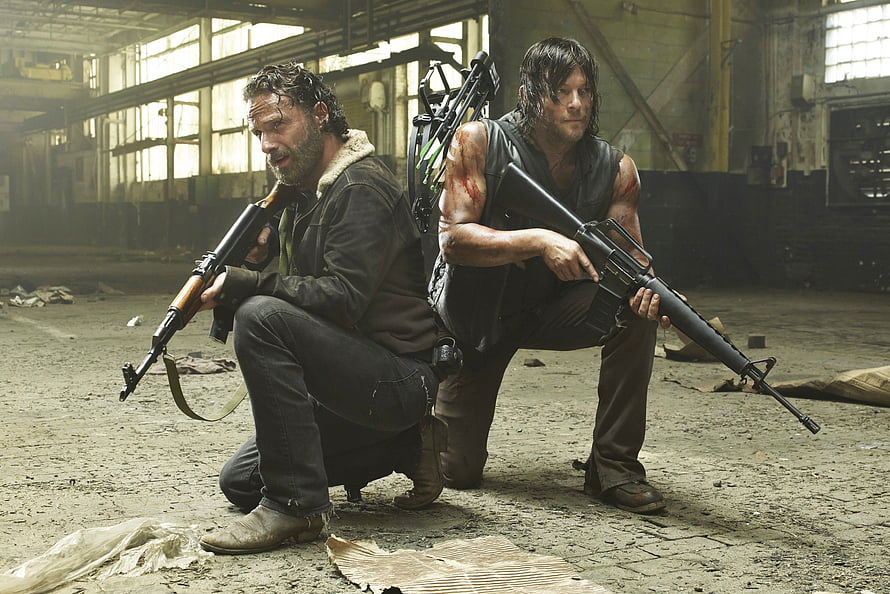 Rick Grimes and Daryl Dixon Crouching with Firearms in Abandoned Warehouse HD wallpaper
