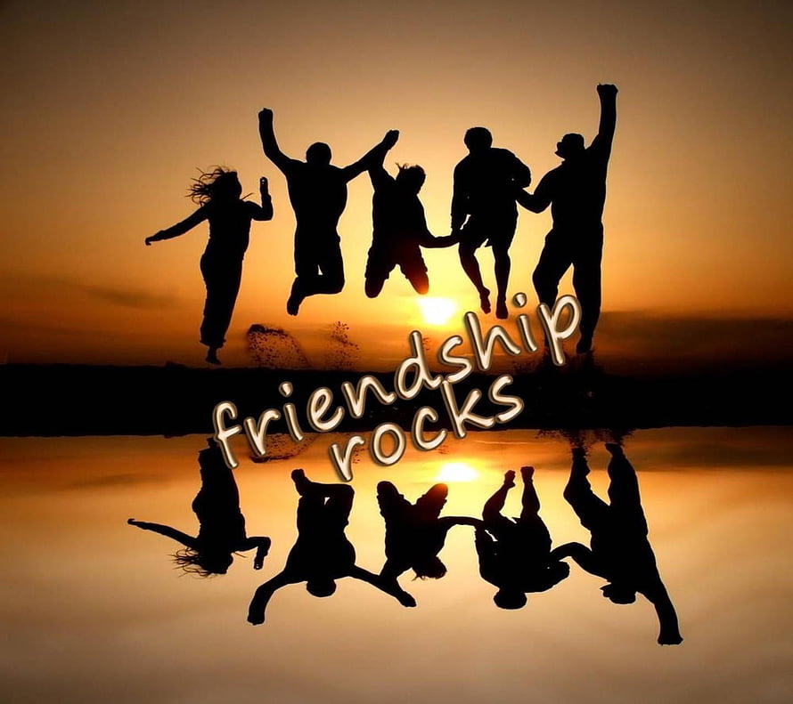 Silhouetted friends jumping at sunset with friendship rocks text and water reflection HD wallpaper