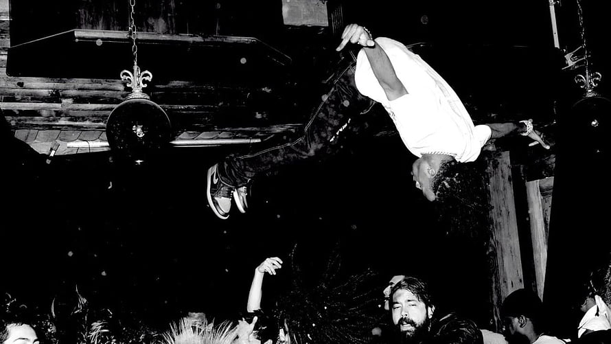 Playboi Carti performing an acrobatic flip over the crowd at a live concert HD wallpaper