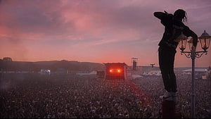 Travis Scott performing at a massive outdoor music festival at sunset with a huge crowd HD wallpaper