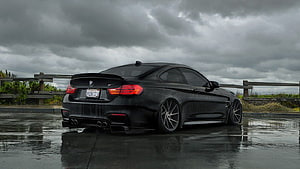 Black BMW M4 CS Coupe Rear Three-Quarter View on Wet Asphalt Under Stormy Sky HD wallpaper