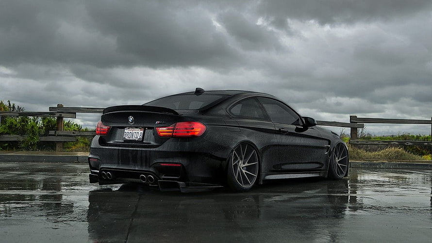 Black BMW M4 CS Coupe Rear Three-Quarter View on Wet Asphalt Under Stormy Sky HD wallpaper