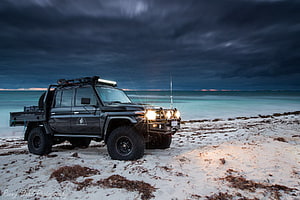 Black Toyota Land Cruiser 79 Series Pickup on a Sandy Beach at Dusk HD wallpaper