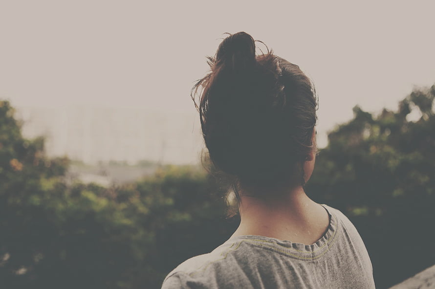 Woman with Messy Bun Hair Looking Out at Scenic Green Landscape HD wallpaper