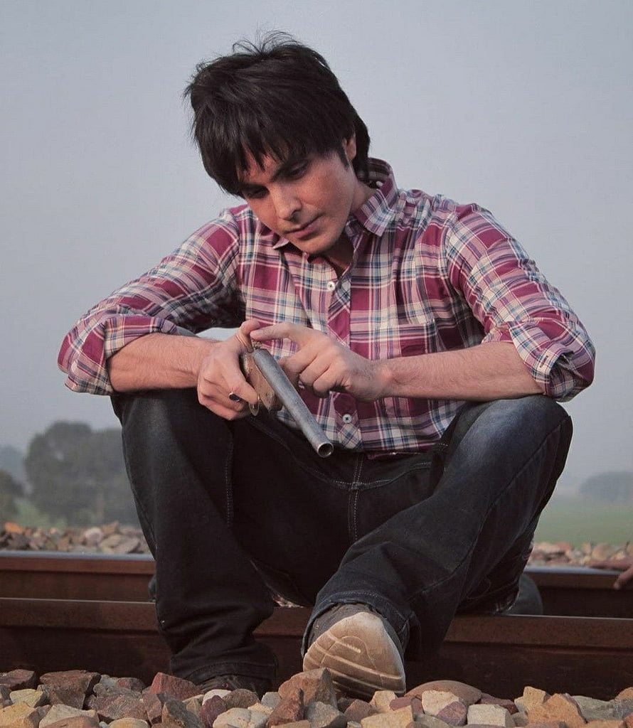 Man in plaid shirt crouching on railroad tracks holding a metal pipe HD phone wallpaper