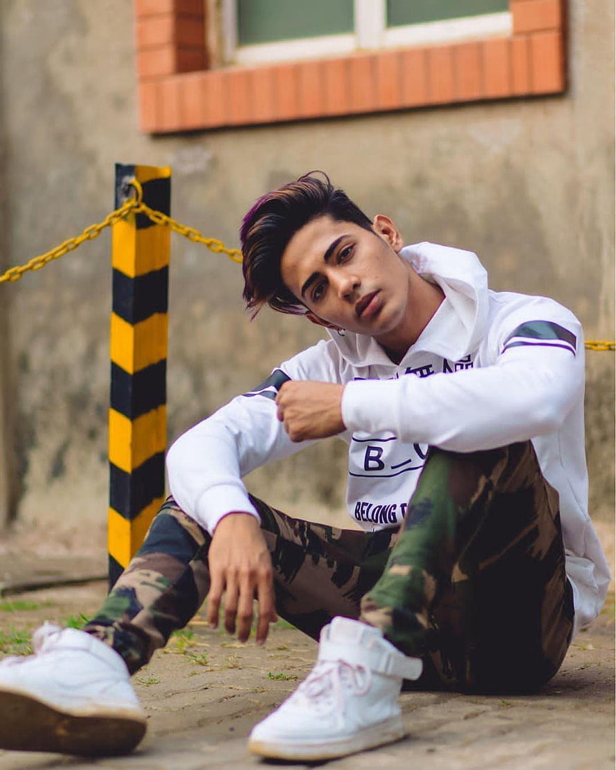 Young man in white hoodie and camouflage pants sitting on pavement HD phone wallpaper