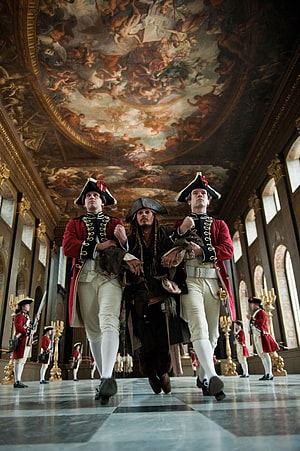 Captain Jack Sparrow flanked by redcoated guards in an ornate baroque palace hall HD phone wallpaper