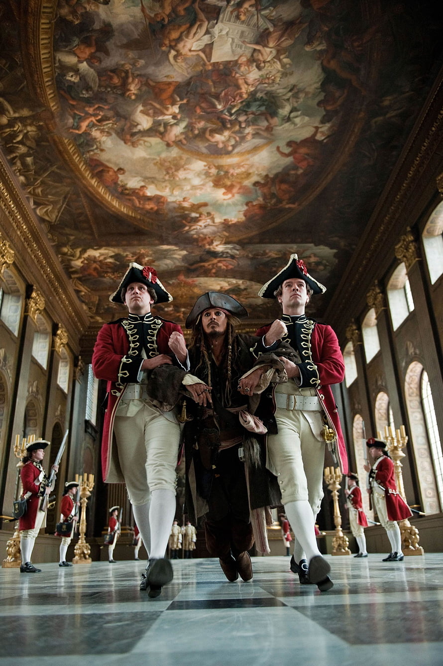 Captain Jack Sparrow flanked by redcoated guards in an ornate baroque palace hall HD phone wallpaper