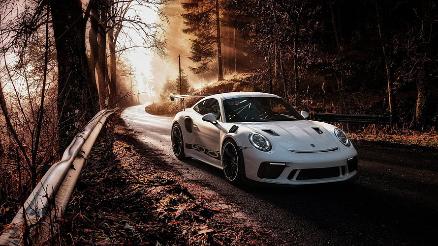 White Porsche 911 GT3 RS on a winding forest road at golden hour HD wallpaper