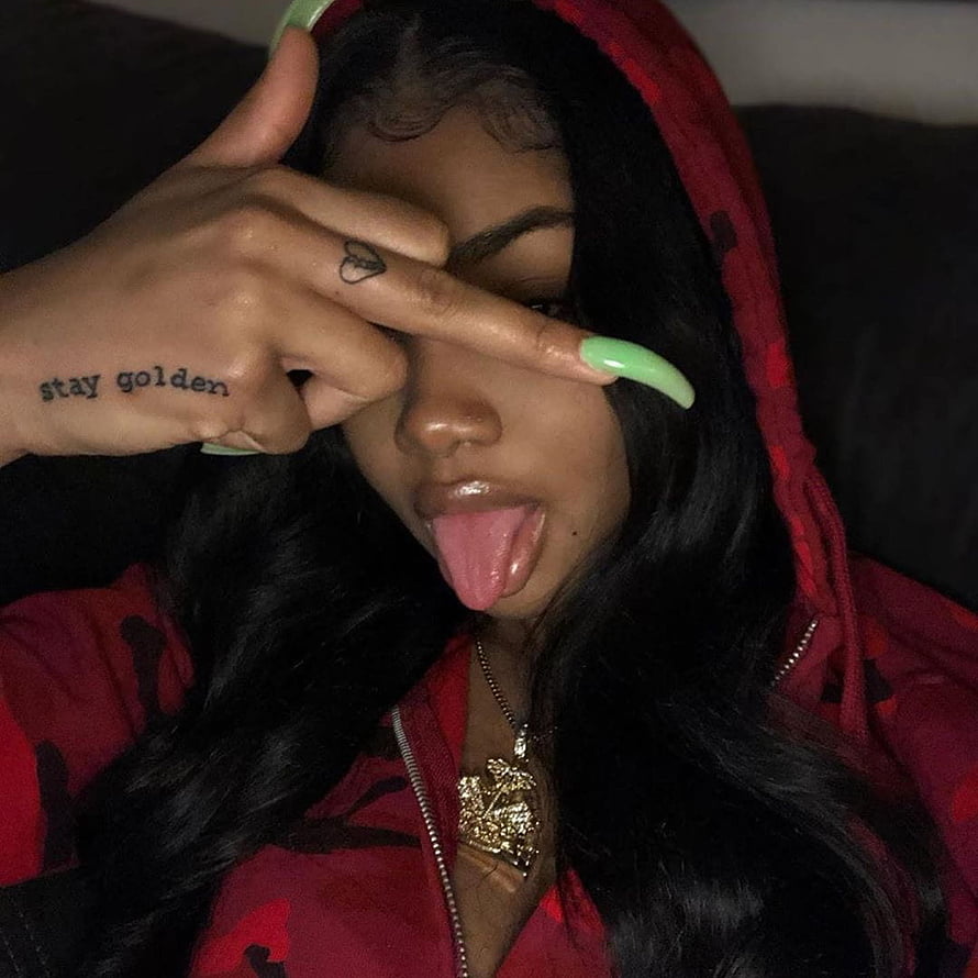 Young woman in red hoodie with long green nails and hand tattoo making a playful face HD phone wallpaper