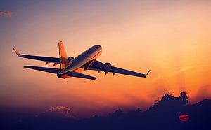 Commercial Jet Aircraft Ascending Through Vibrant Sunset Sky With Dramatic Clouds HD wallpaper