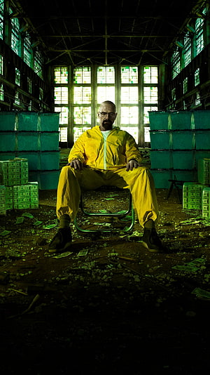 Walter White in Yellow Hazmat Suit Seated in Abandoned Warehouse with Stacks of Cash HD phone wallpaper