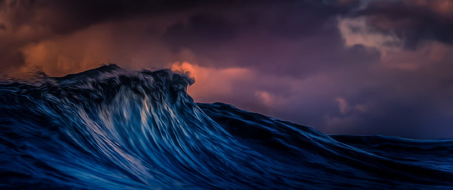 Dramatic Ocean Wave Curling Under a Stormy Sunset Sky HD wallpaper