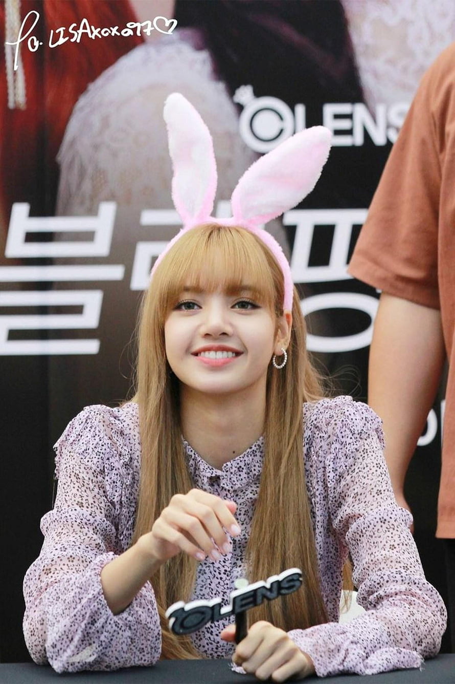 Lisa from BLACKPINK smiling at a fan signing event wearing pink bunny ears and a floral blouse HD phone wallpaper