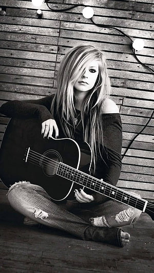Avril Lavigne Sitting Cross-Legged With Acoustic Guitar Against Rustic Wooden Wall HD phone wallpaper