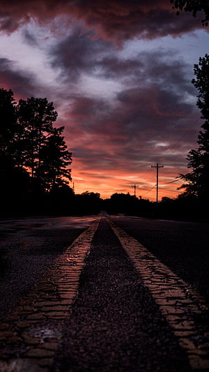 Moody Country Road at Dusk with Dramatic Sunset Sky and Silhouetted Trees HD phone wallpaper