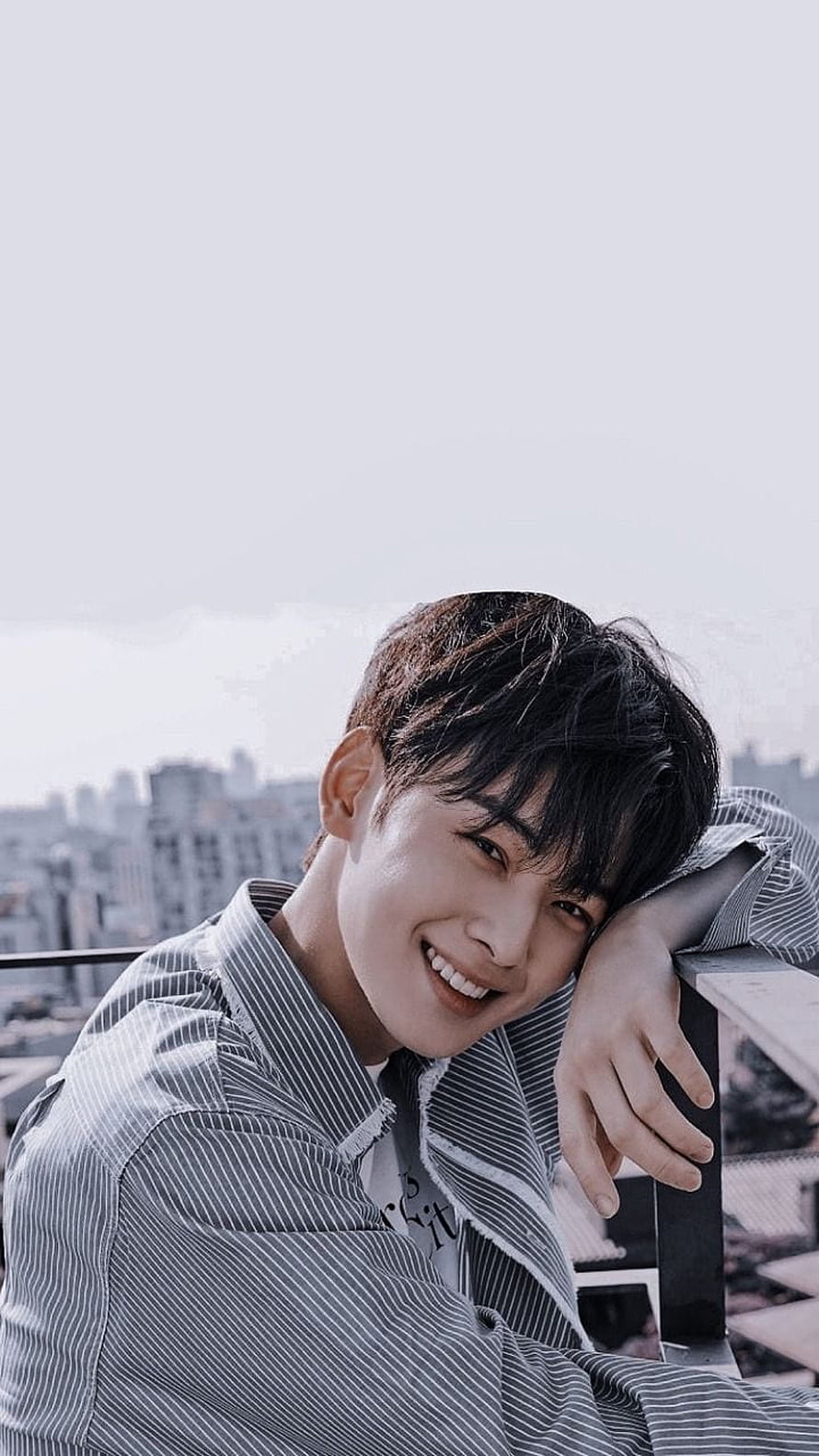 Cha Eun Woo smiling portrait on a rooftop with city skyline backdrop HD phone wallpaper