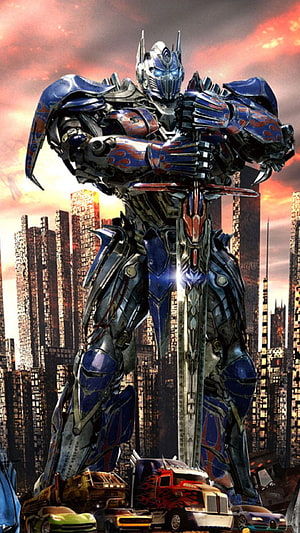 Optimus Prime Standing Over Destroyed City with Sword and Vehicles HD phone wallpaper