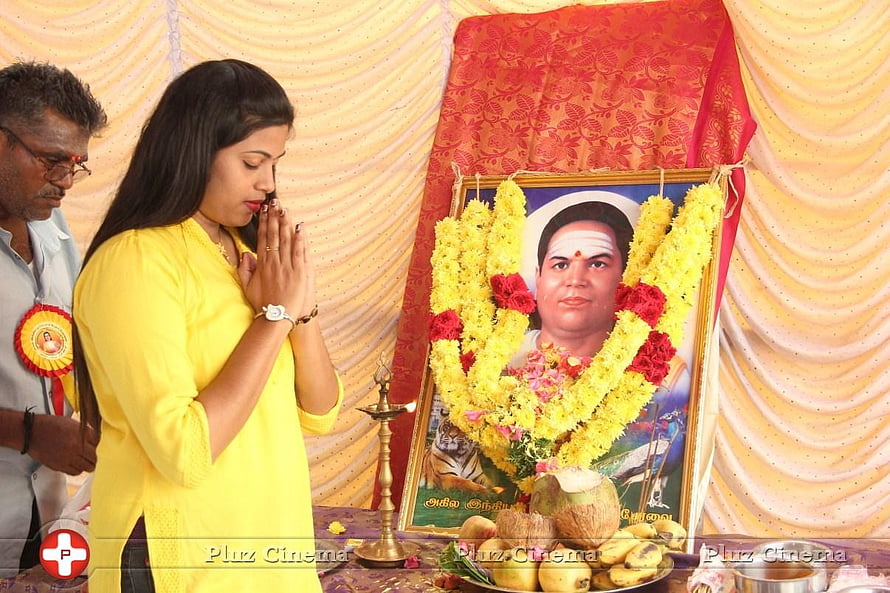 Woman in yellow offering prayers at a memorial altar with floral garlands and fruit offerings HD wallpaper
