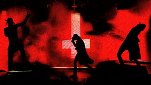 Silhouetted Performers on Stage with Red Lighting and Cross Backdrop HD wallpaper