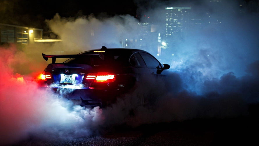 Black BMW M3 performing a drift with thick smoke at night in an urban setting HD wallpaper