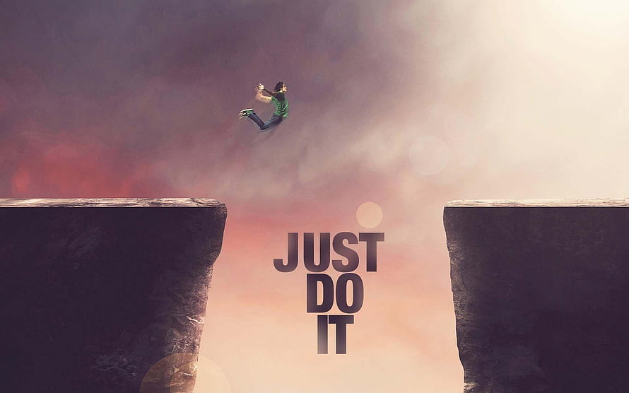 Person Leaping Across a Chasm with Just Do It Text in a Dramatic Sunset Sky HD wallpaper