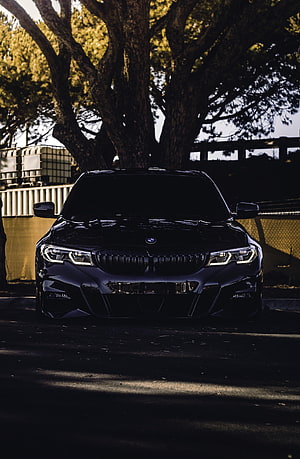 Black BMW 330i G20 Front View Under Tree With Dramatic Lighting HD phone wallpaper