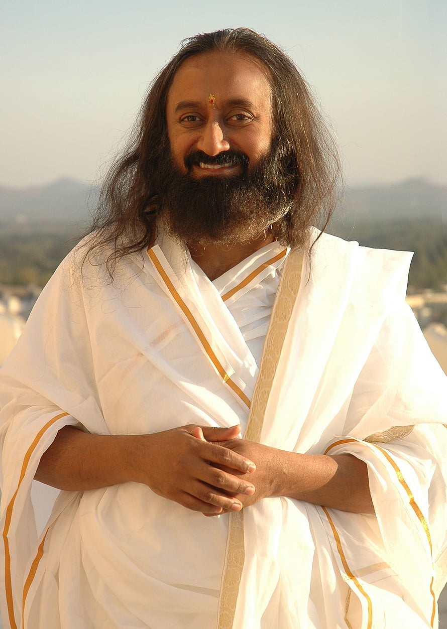 Sri Sri Ravi Shankar in white robes with gold trim standing outdoors HD phone wallpaper